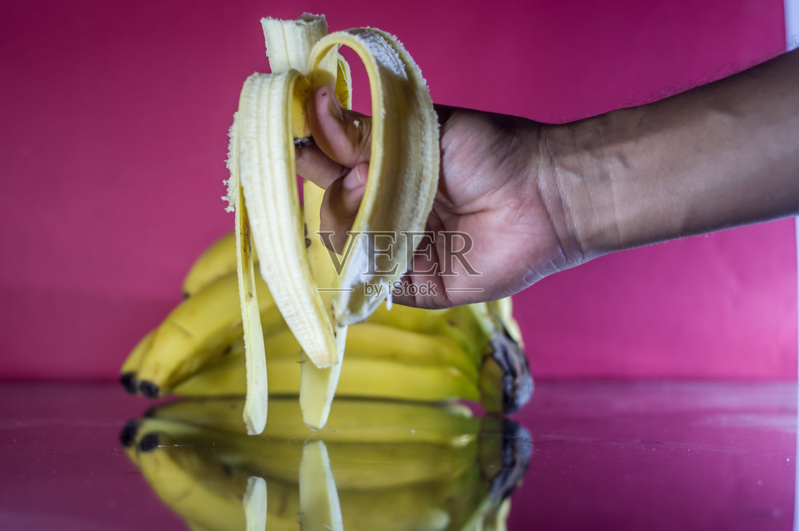 桌上一串香蕉，映衬着红色的背景照片摄影图片