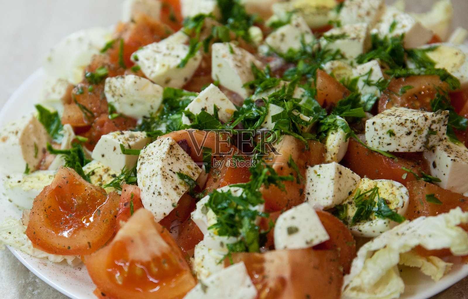 开胃沙拉，羊乳酪，西红柿，鸡蛋，香草在一个盘子在桌子上，特写。健康food.blur照片摄影图片