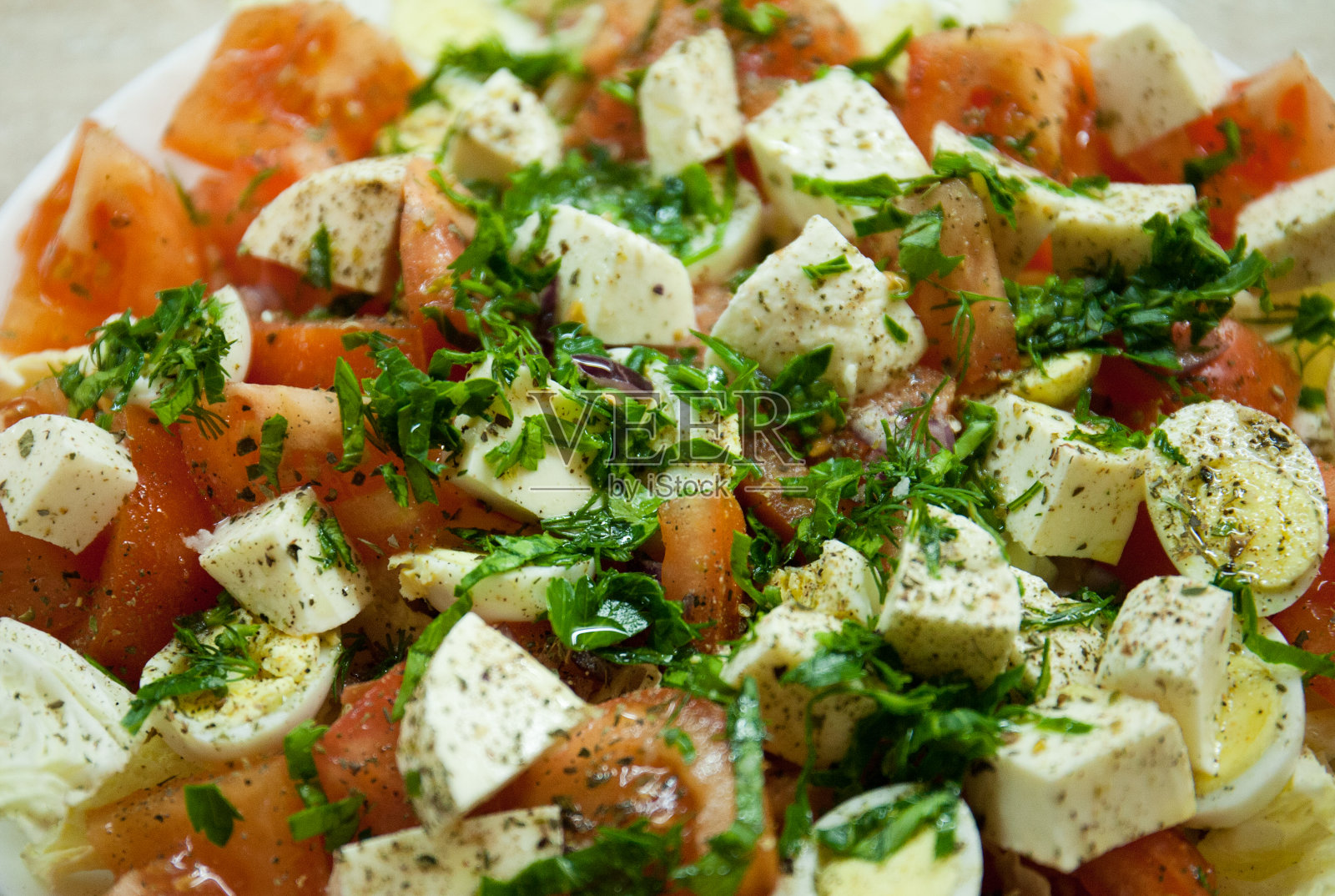 健康饮食。菲达奶酪沙拉，西红柿，鸡蛋，香草放在盘子里。做一顿美味佳肴的原料。照片摄影图片