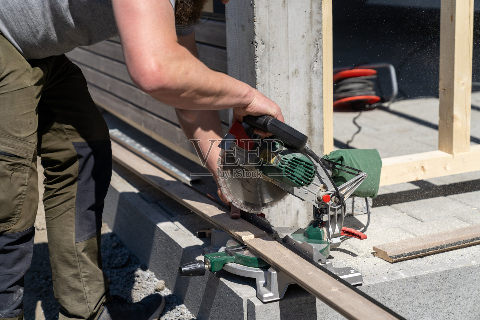 坚韧的建筑工人在建造车库时用斜锯切割木墙板照片摄影图片