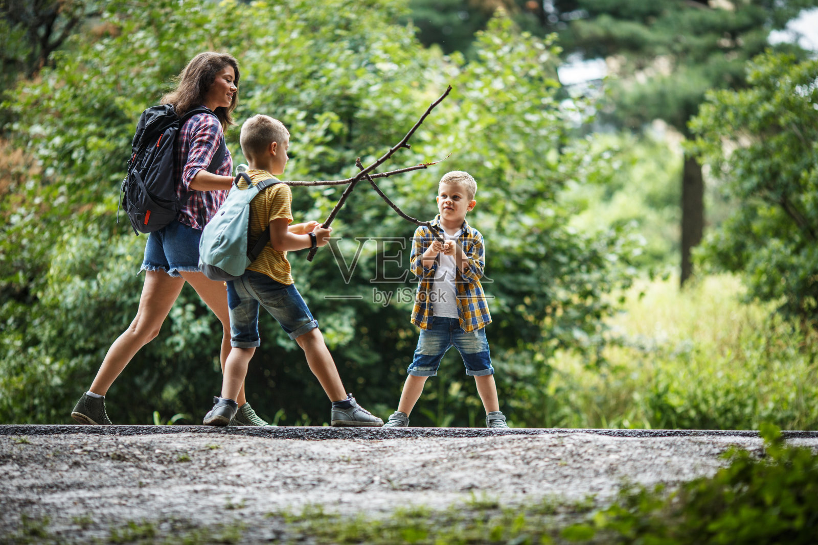 母亲和她的小儿子们在乡间小路上徒步旅行。照片摄影图片