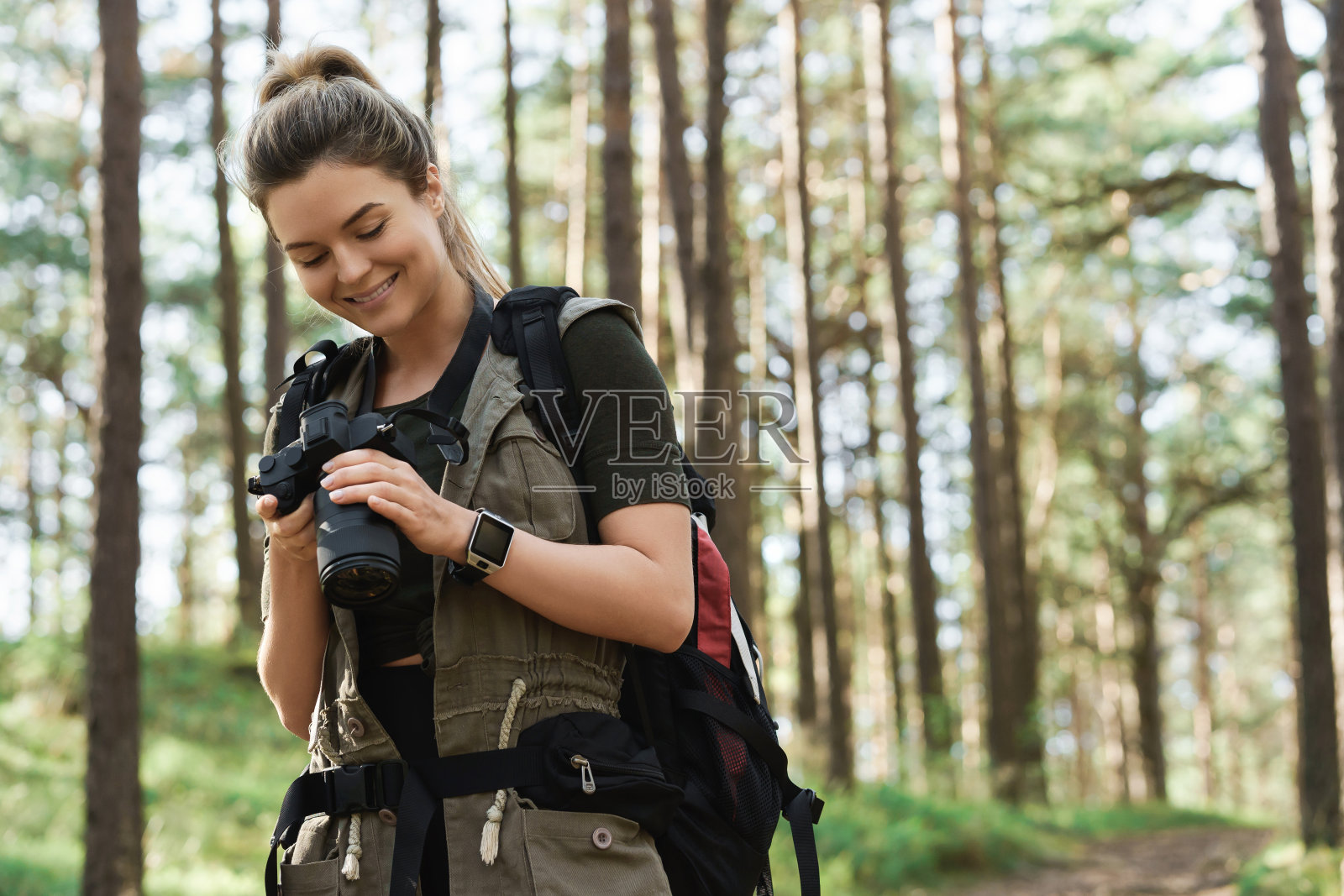 徒步旅行者在绿色森林中使用现代无反光镜相机照片摄影图片