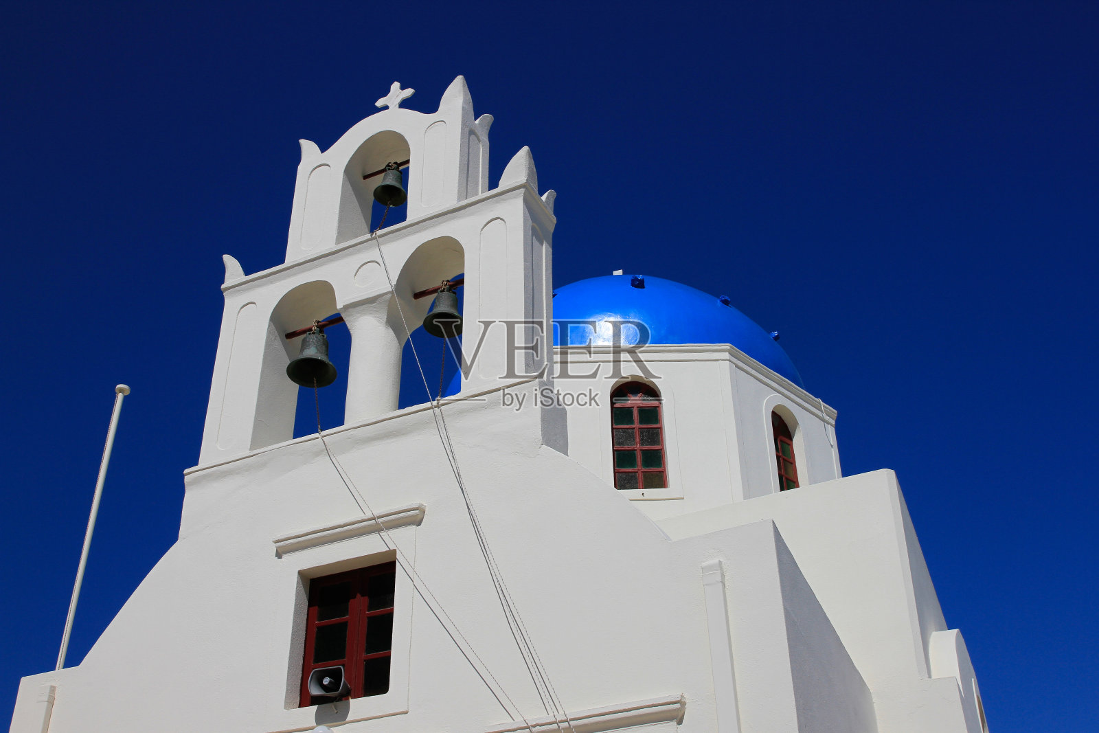 希腊圣托里尼岛伊亚的蓝色天空映衬着传统的白色希腊教堂的钟楼和蓝色圆顶照片摄影图片