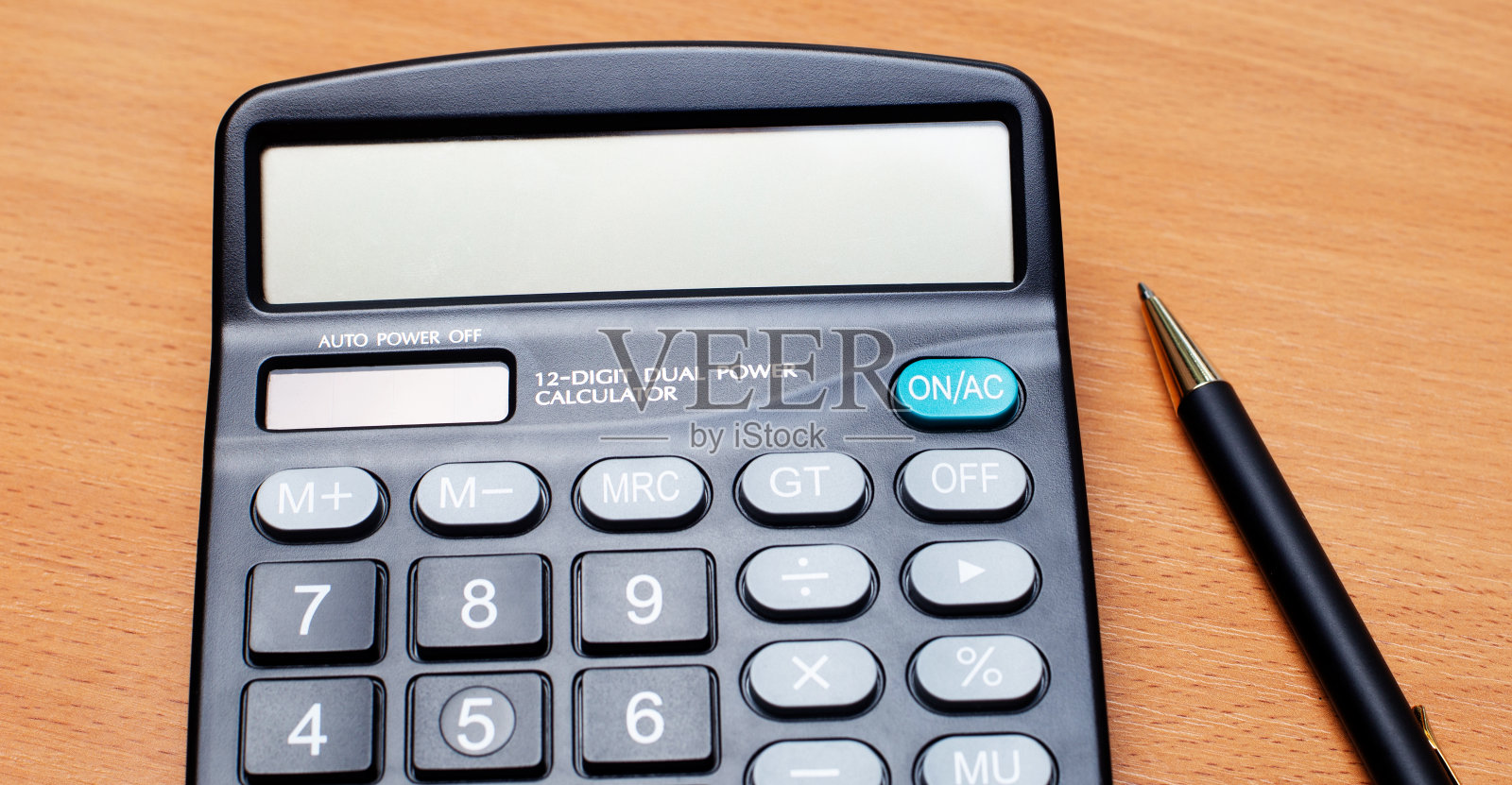 木桌上放着一支黑色的钢笔和一个可以插入文本的计算器。模板。经营理念照片摄影图片