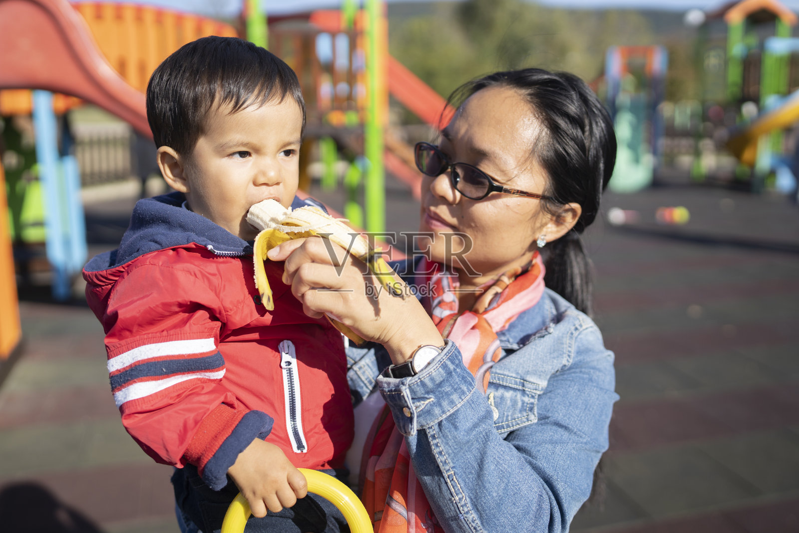 一位母亲抱着正在吃香蕉的儿子照片摄影图片