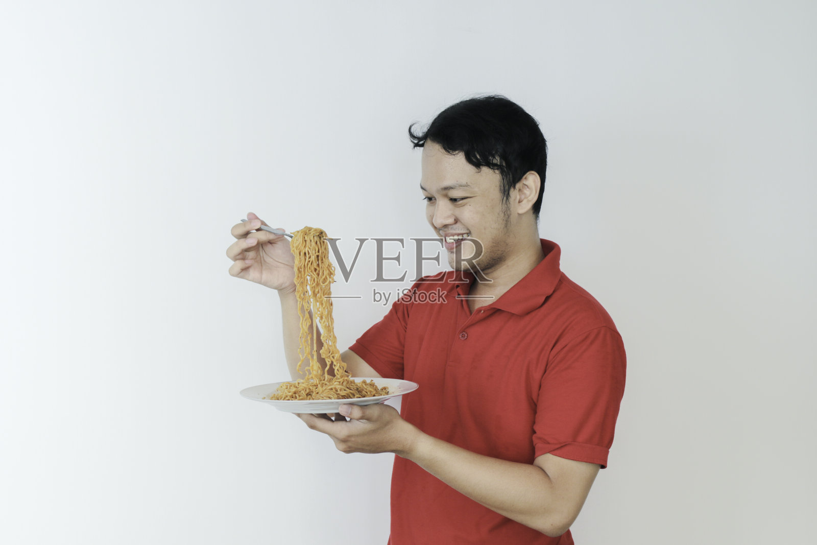 快乐的年轻亚洲男子享受面条肖像。吃午饭的概念。照片摄影图片