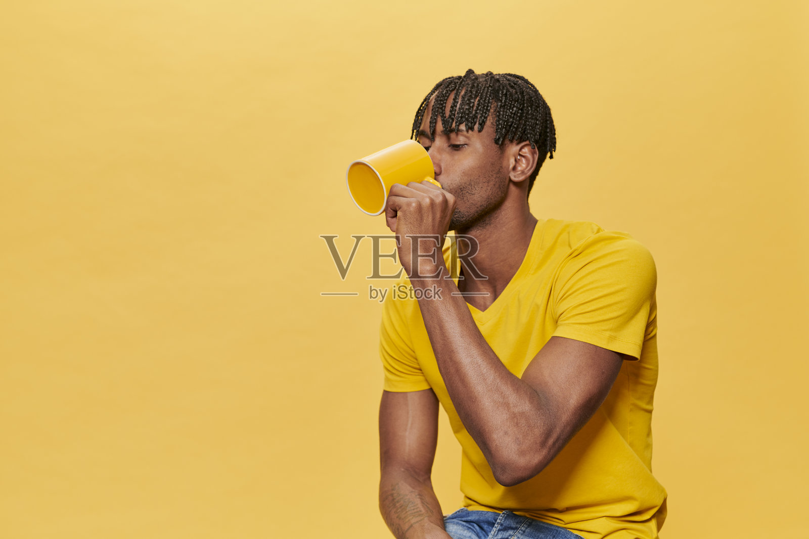 帅气的非洲男子穿着黄色t恤和黄色杯子在黄色背景照片摄影图片