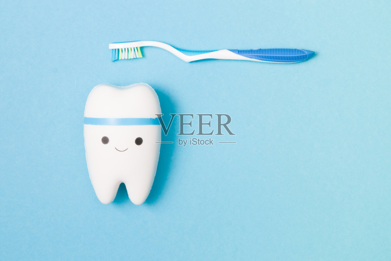 糖果、牙刷、牙线和蓝色背景上的玩具牙齿，带微笑的牙齿模型，保护口腔免受龋齿的概念，儿童牙科广告照片摄影图片