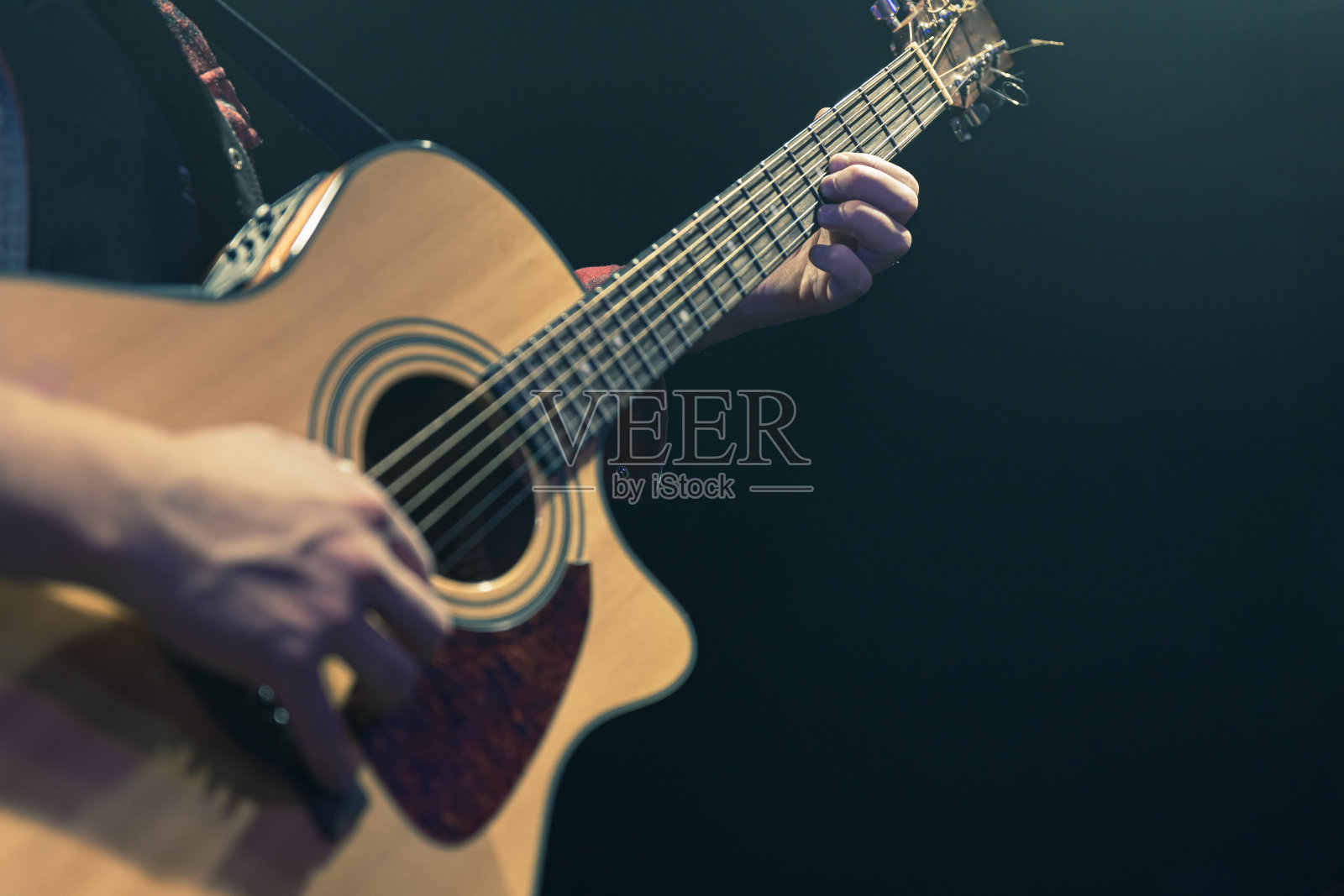 在黑暗中弹奏原声吉他的吉他手。照片摄影图片
