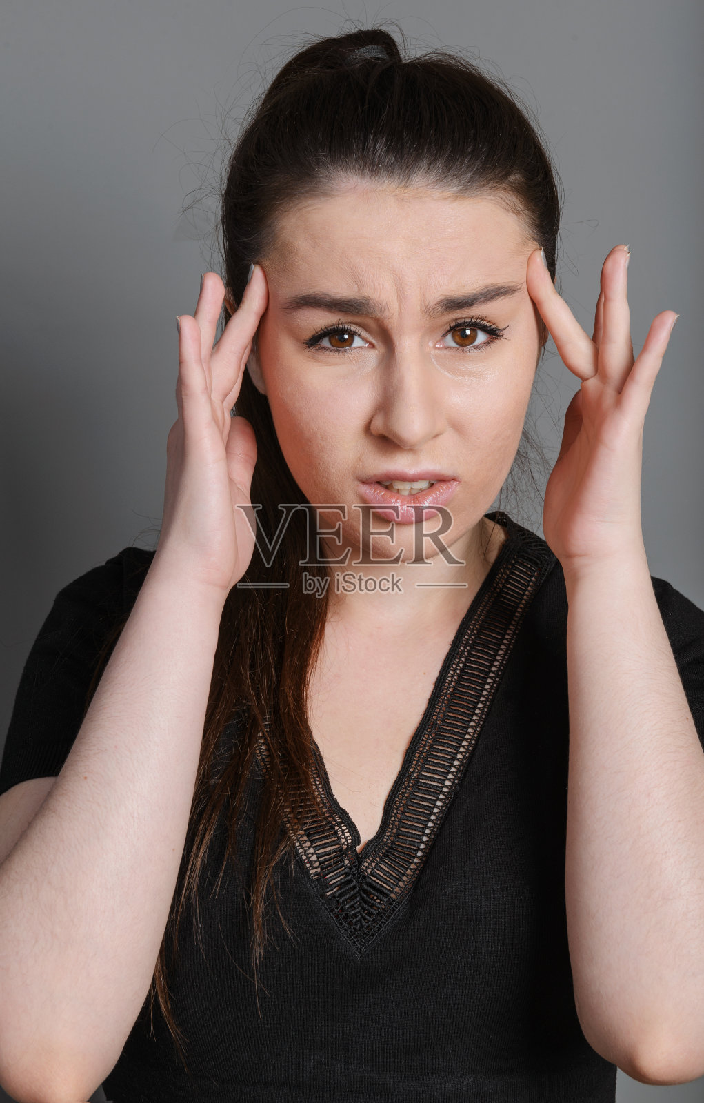 25岁的年轻女子抱着她的头，女孩头疼照片摄影图片