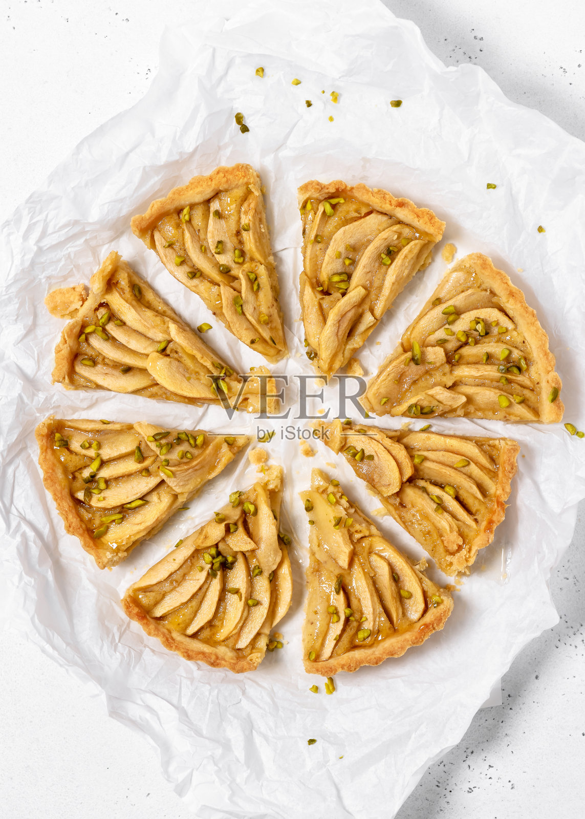 把新鲜的自制苹果派切成许多块，放在烤纸上。照片摄影图片