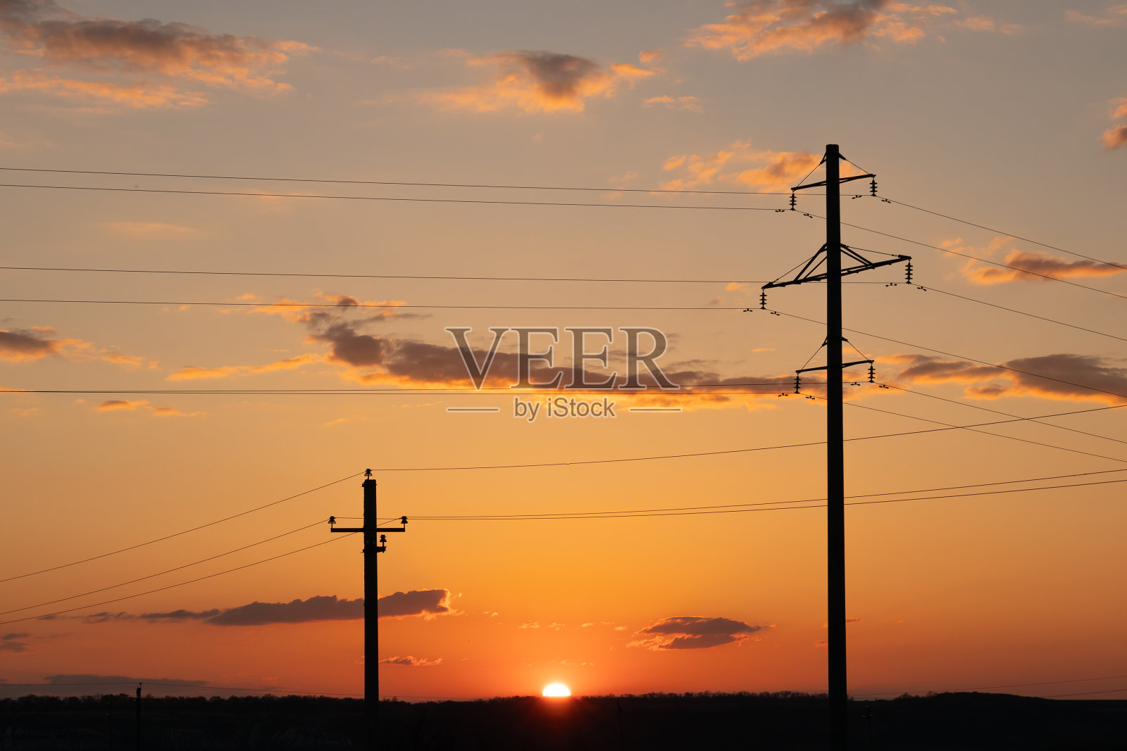 夕阳背景下的两根混凝土电线杆。照片摄影图片