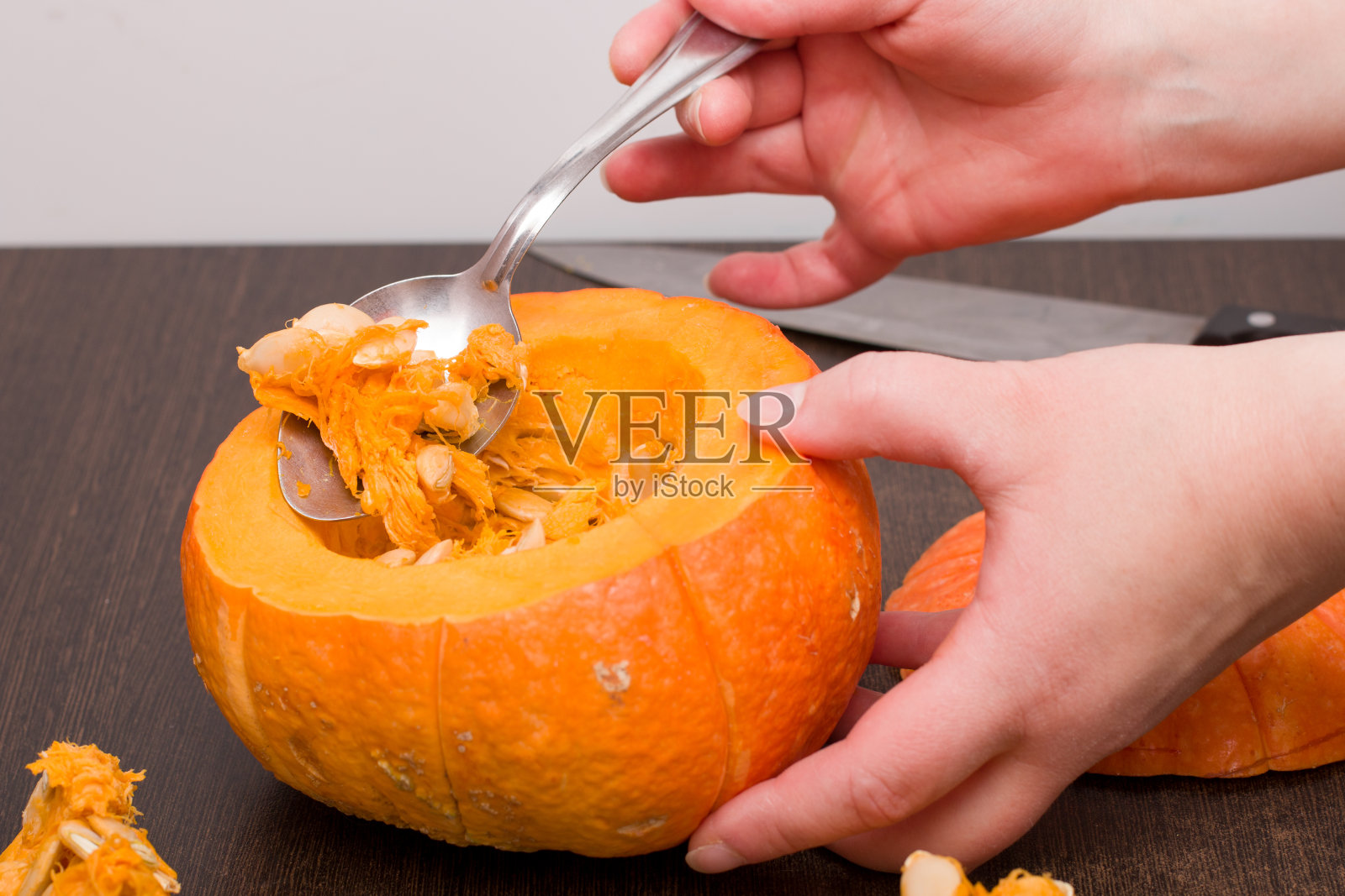 女人们用勺子拔出勺子刷南瓜种子，勺子上美味的南瓜和铁刀的背景照片摄影图片