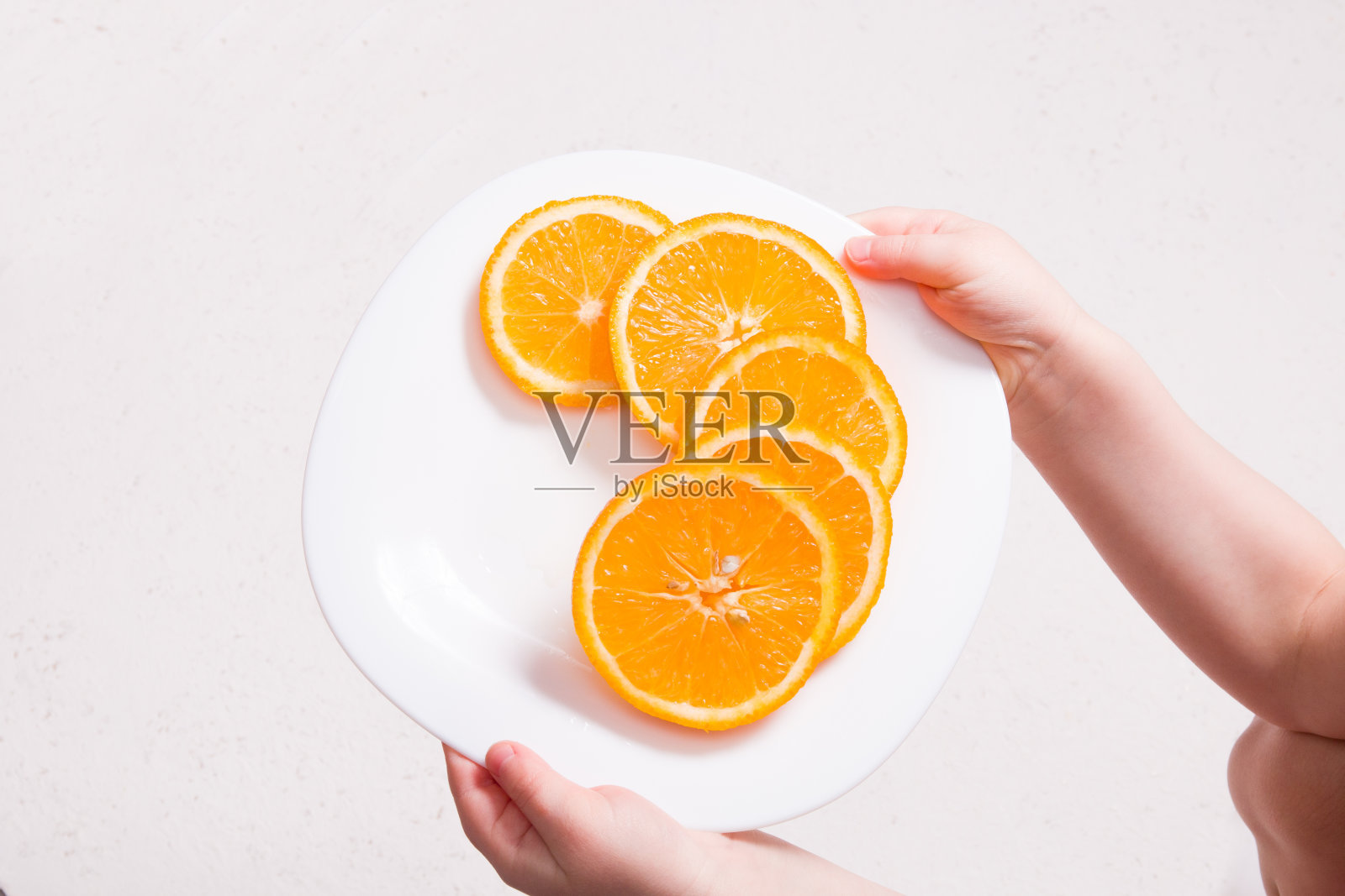 小孩拿着一个白色盘子，上面有几片橙色的空白背景照片摄影图片