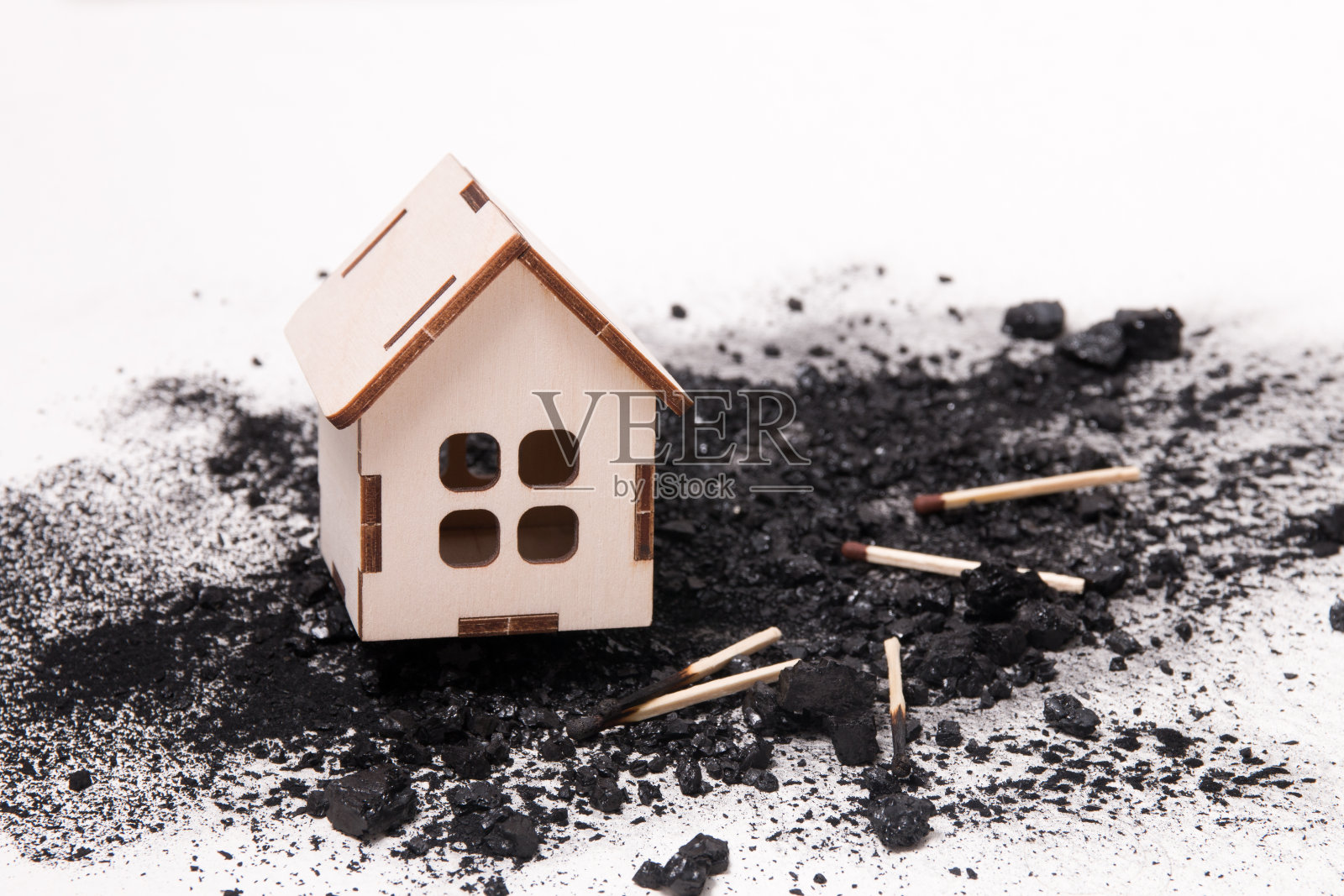 木屋模型上一堆煤和火柴，白色背景复制空间，房地产火灾保险概念照片摄影图片