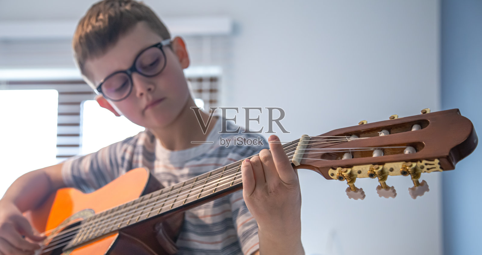 小男孩在学弹古典吉他。照片摄影图片