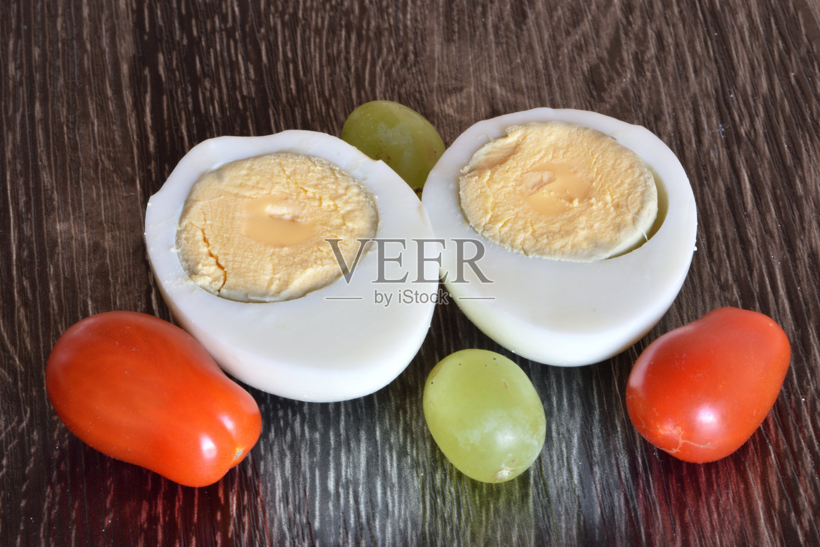 用西红柿和葡萄装饰的两半煮鸡蛋照片摄影图片