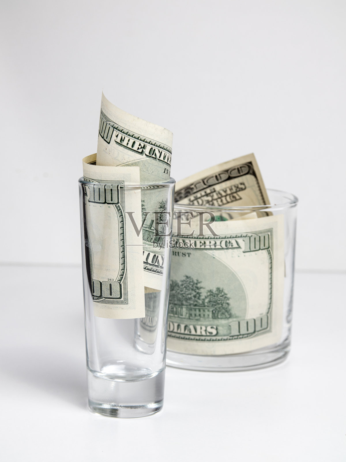 100美元装在威士忌酒杯里照片摄影图片