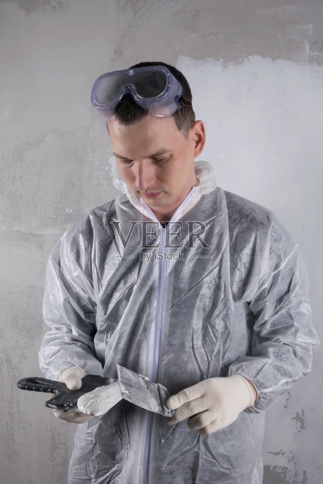 一个工人用泥铲抹灰泥来修补混凝土墙照片摄影图片