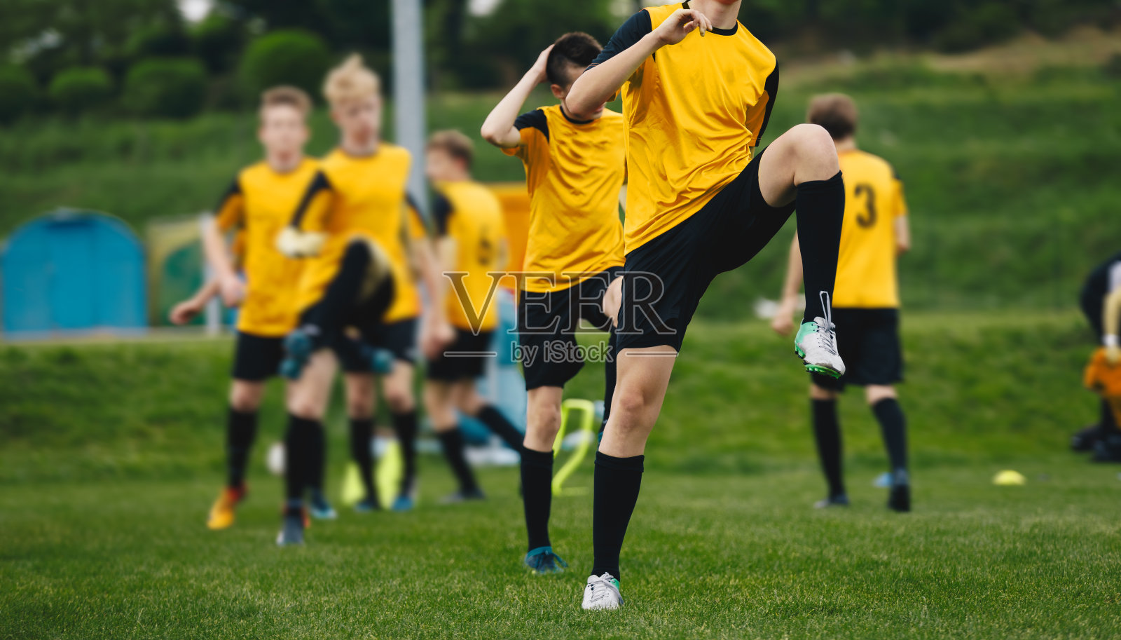 一群青少年足球运动员正在训练。男孩伸展练习单元在比赛前。年轻运动员一起在草地上练习照片摄影图片
