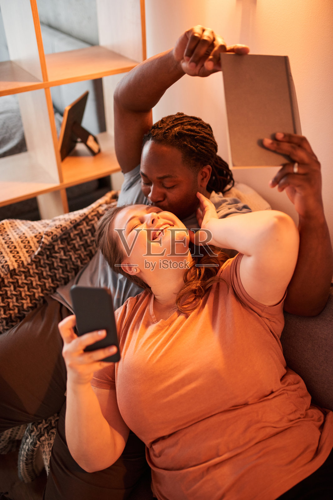 男人亲吻他可爱的女人，同时在平板电脑前自拍照片摄影图片