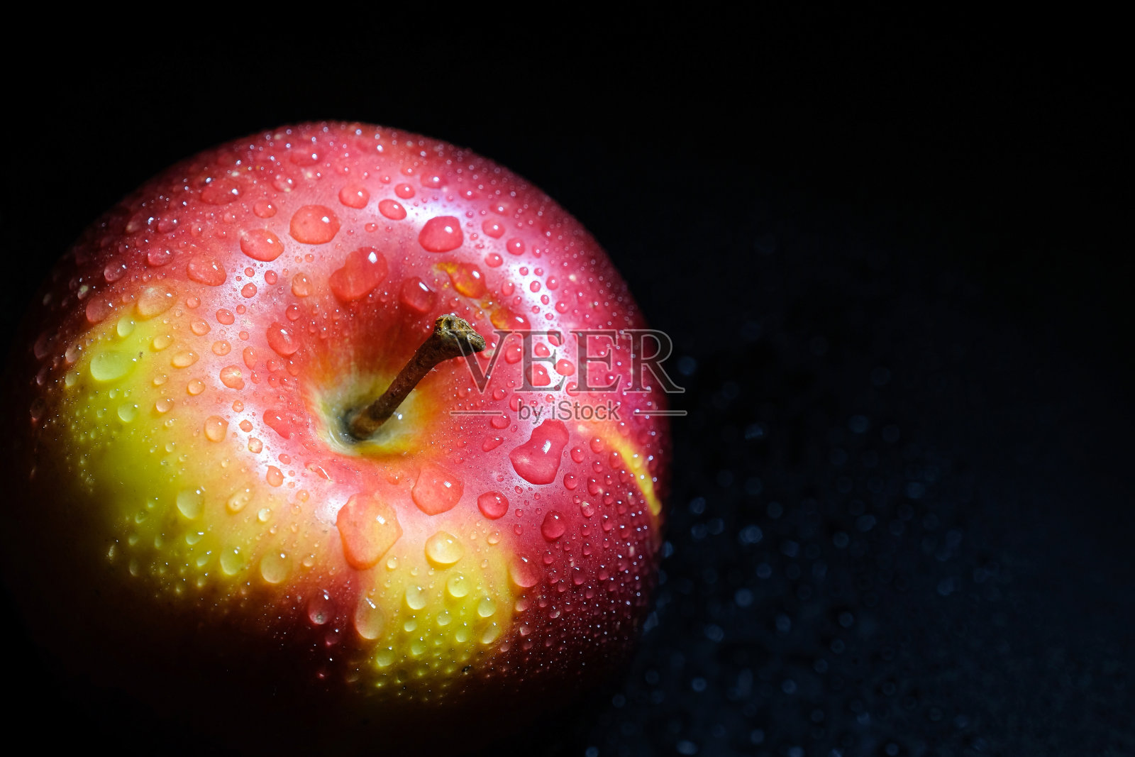 成熟的苹果和水滴在一个黑色的背景，特写。健康饮食照片摄影图片