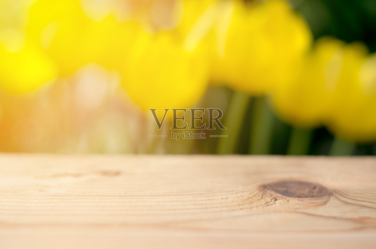 木桌子的特写与黄色郁金香模糊的背景。黄色自然模糊背景与木桌产品广告照片摄影图片