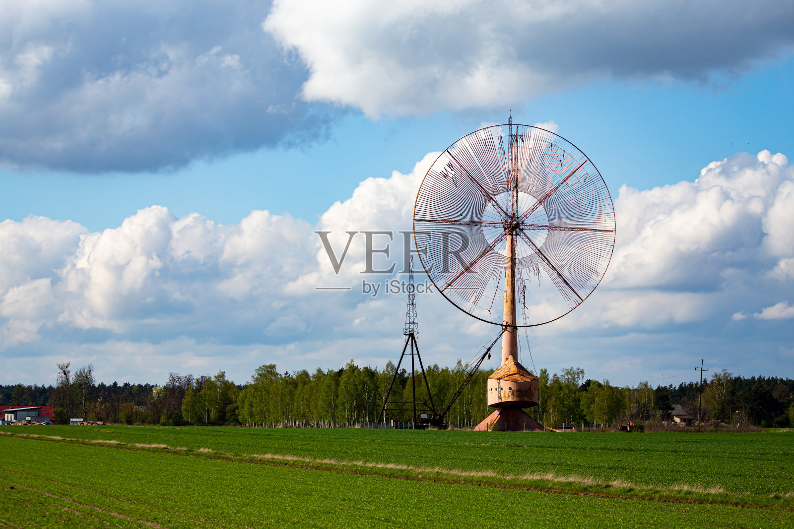一个古老的、封闭的风电场孤零零地矗立在田野里。物体与天空与微小的云。照片摄影图片