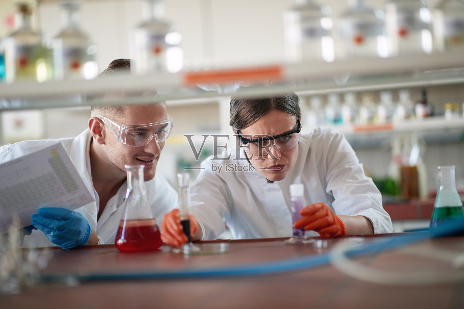 年轻的化学学生戴着防护装备在大学实验室里分析化学反应。科学，化学，实验室，人类照片摄影图片