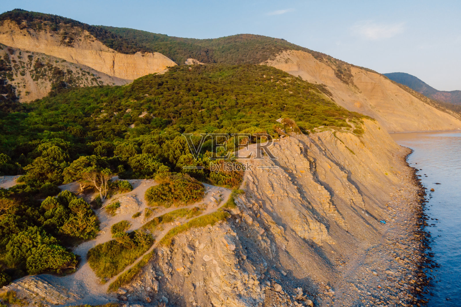 鸟瞰图的海岸线与海洋，山脉，峡谷和悬崖与日落的光照片摄影图片