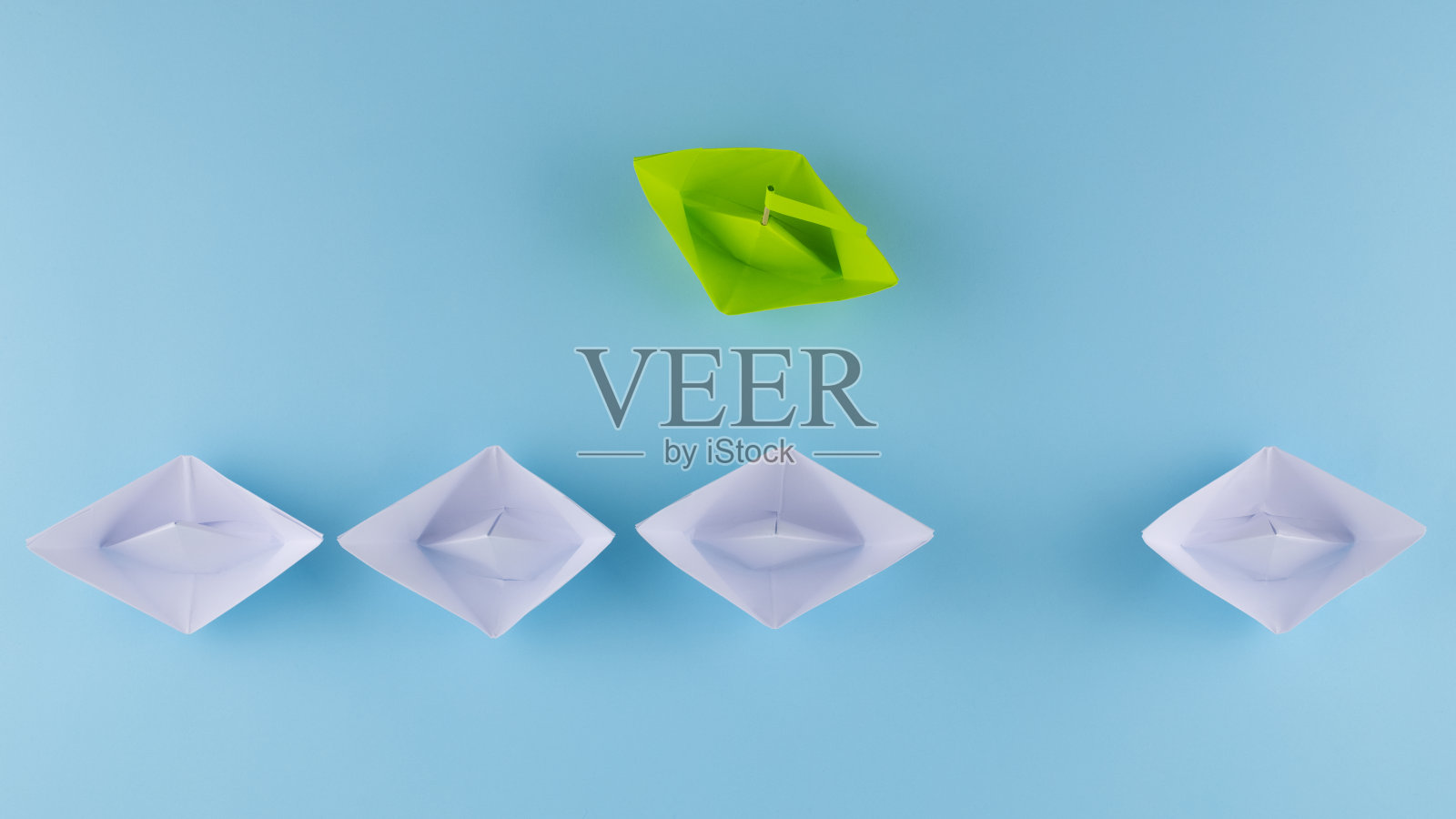 一组指向一个方向的白纸船，一艘绿色的纸船。创新解决方案概念背后的业务照片摄影图片