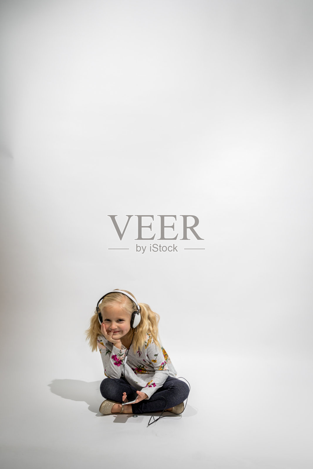 小女孩戴着耳机听白色背景音乐照片摄影图片