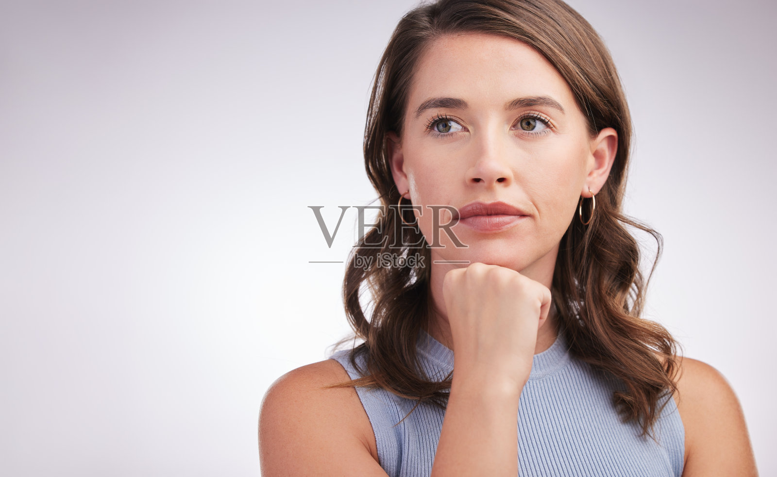 一名年轻女子在灰色背景下看上去若有所思照片摄影图片