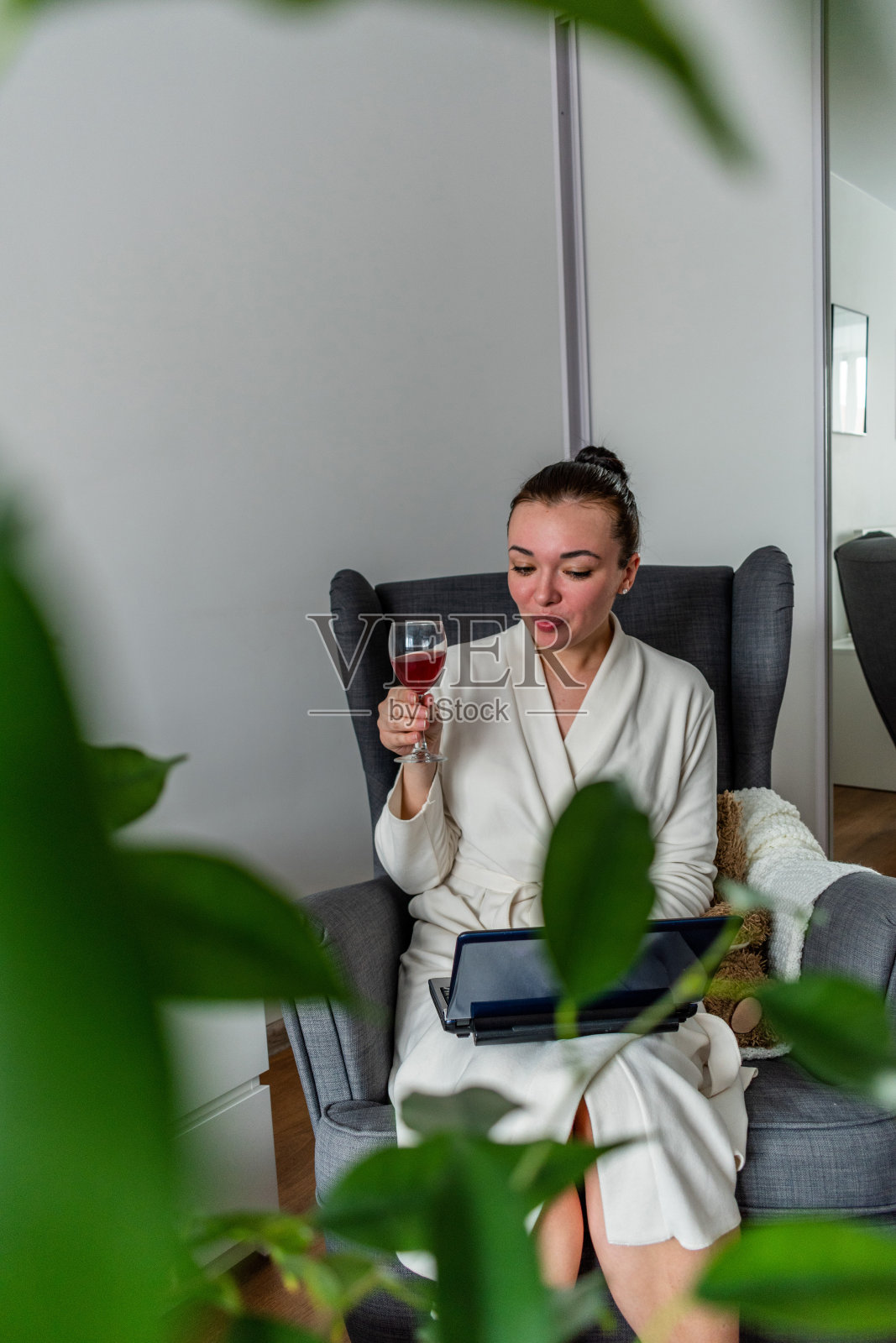 年轻女子手里拿着一杯酒，用笔记本电脑与朋友在线交流。照片摄影图片