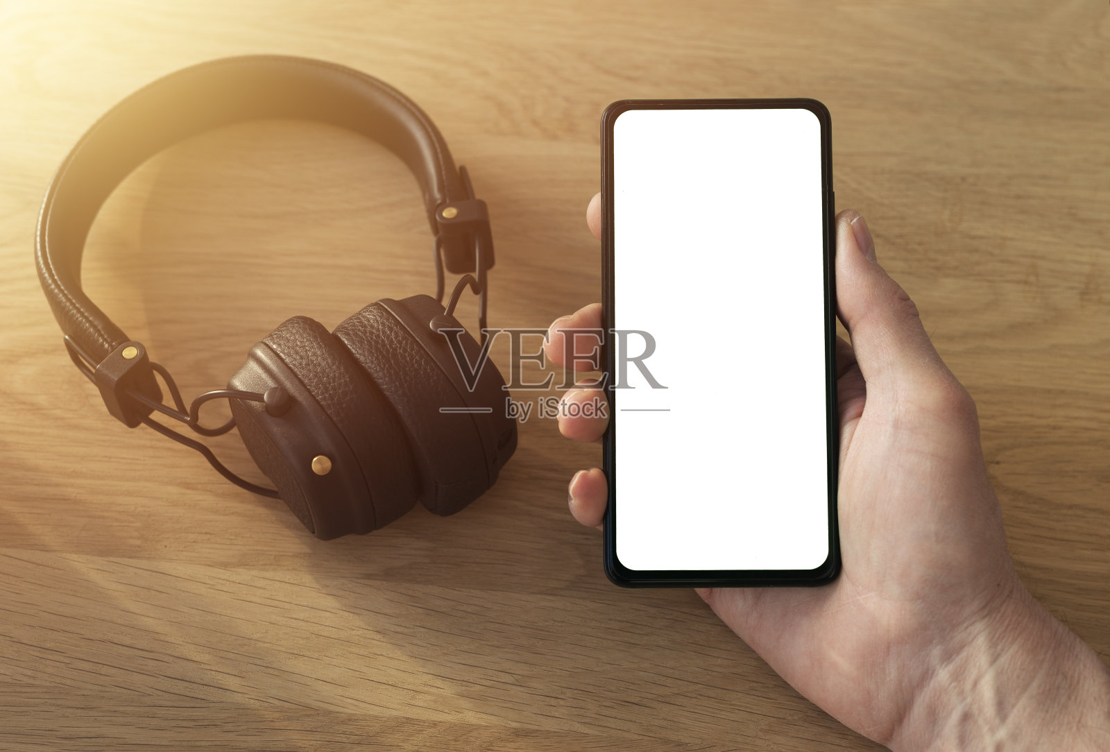 手机模拟与白色屏幕为您的应用程序或网站在男性的手与现代耳机附近听音乐或播客照片摄影图片