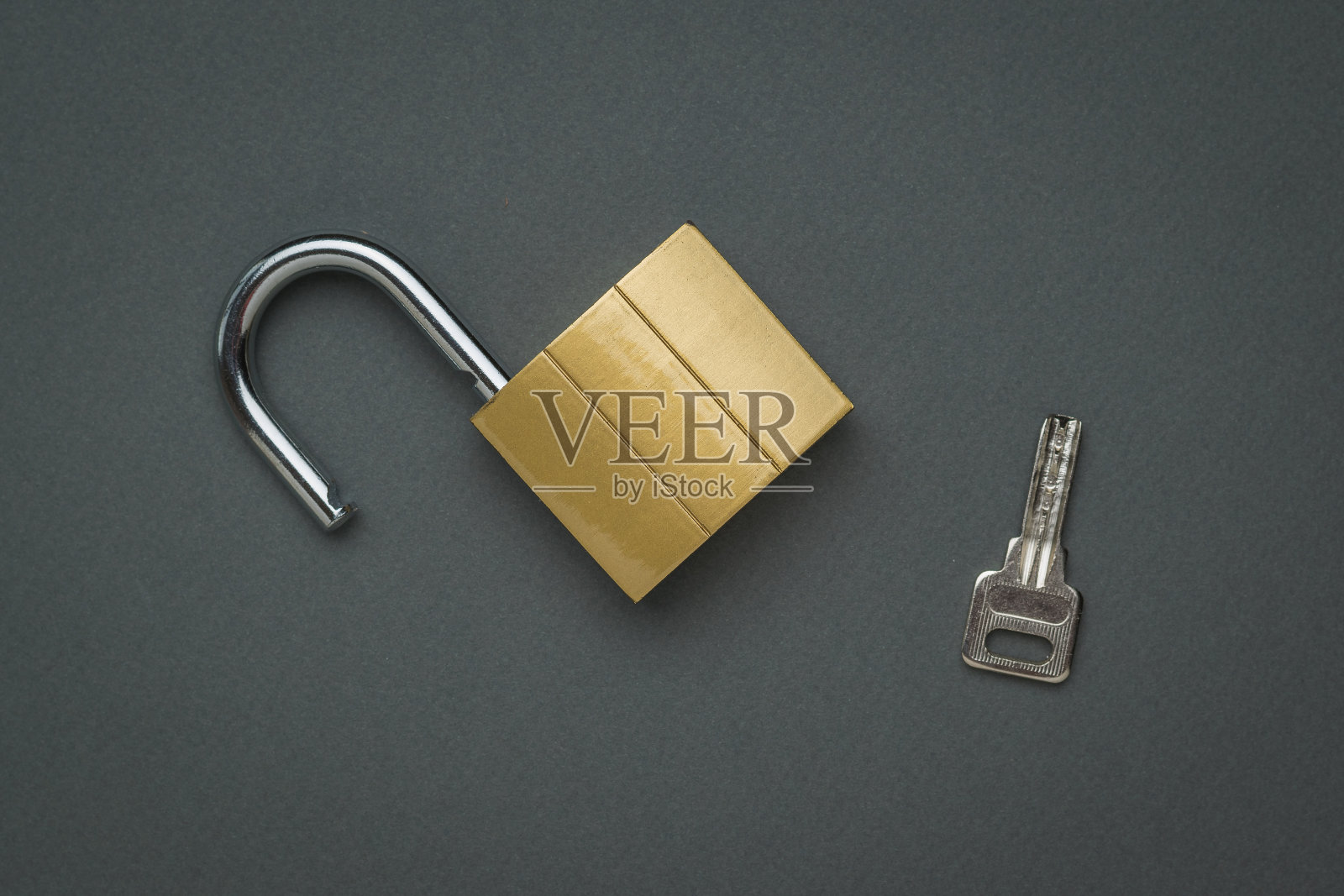 一个打开的锁和钥匙在一个深灰色的背景。平的。照片摄影图片