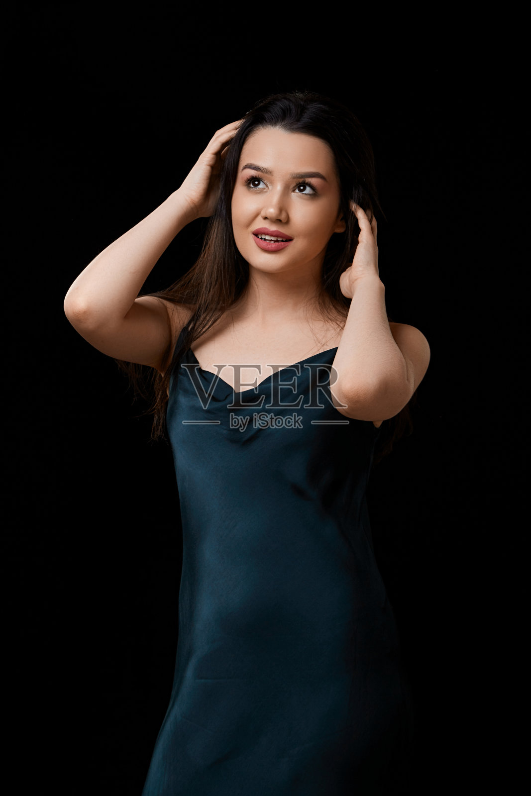 穿着深蓝色连衣裙的年轻女子。在一个孤立的黑色背景上。她是快乐的照片摄影图片