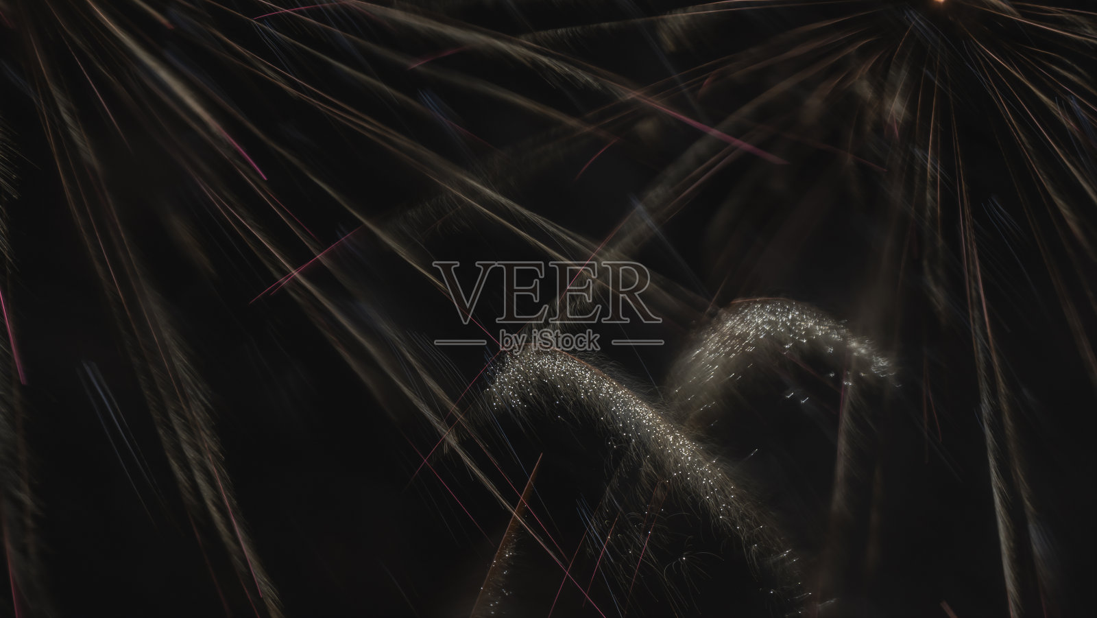 在黑色天空下长时间燃放烟花。夜空下的烟火表演。庆祝的概念。照片摄影图片