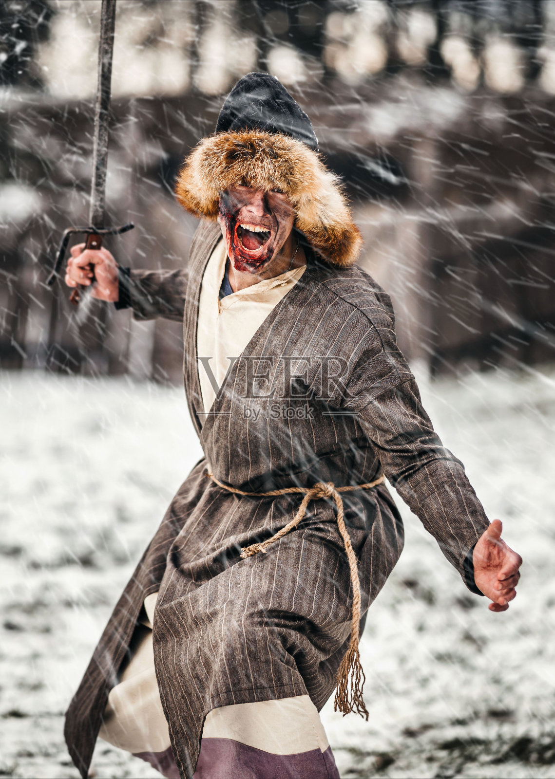 一个戴着帽子脸上抹了油的年轻战士的邪恶情绪，带着剑去战斗。战斗在冬天的背景照片摄影图片