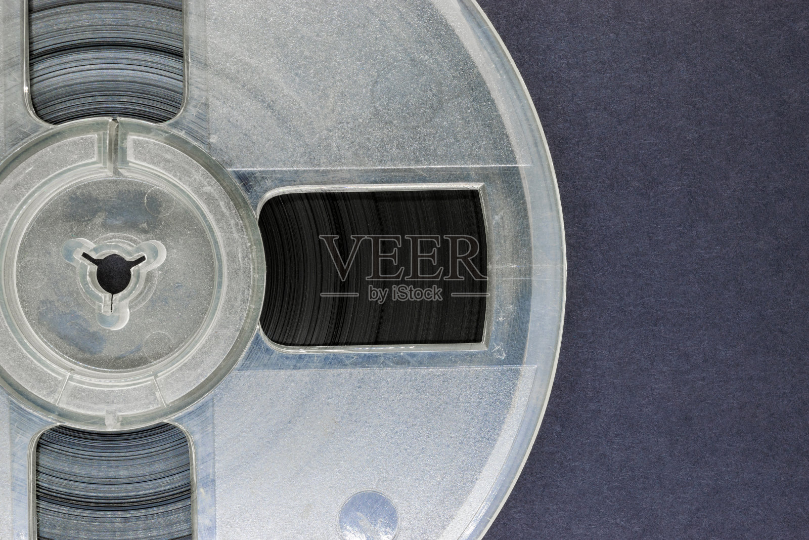 旧的、划伤的、积满灰尘的磁带录音机的旋转盘，音乐唱片放置在灰色的背景表面上，有自由的空间照片摄影图片