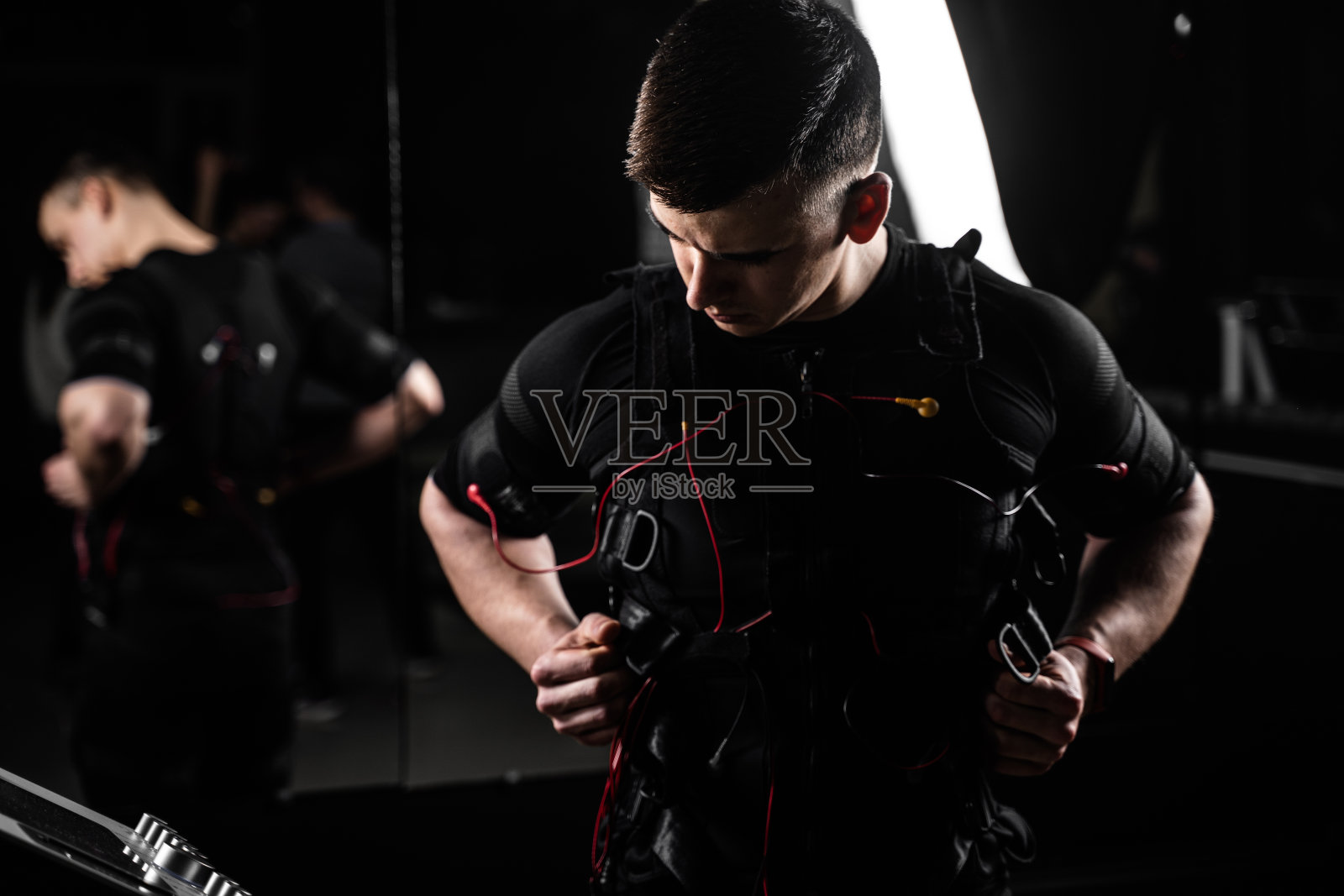 肌肉男健身教练在健身房穿着ems电体服。在衣服上有接触器的电脉冲刺激。照片摄影图片