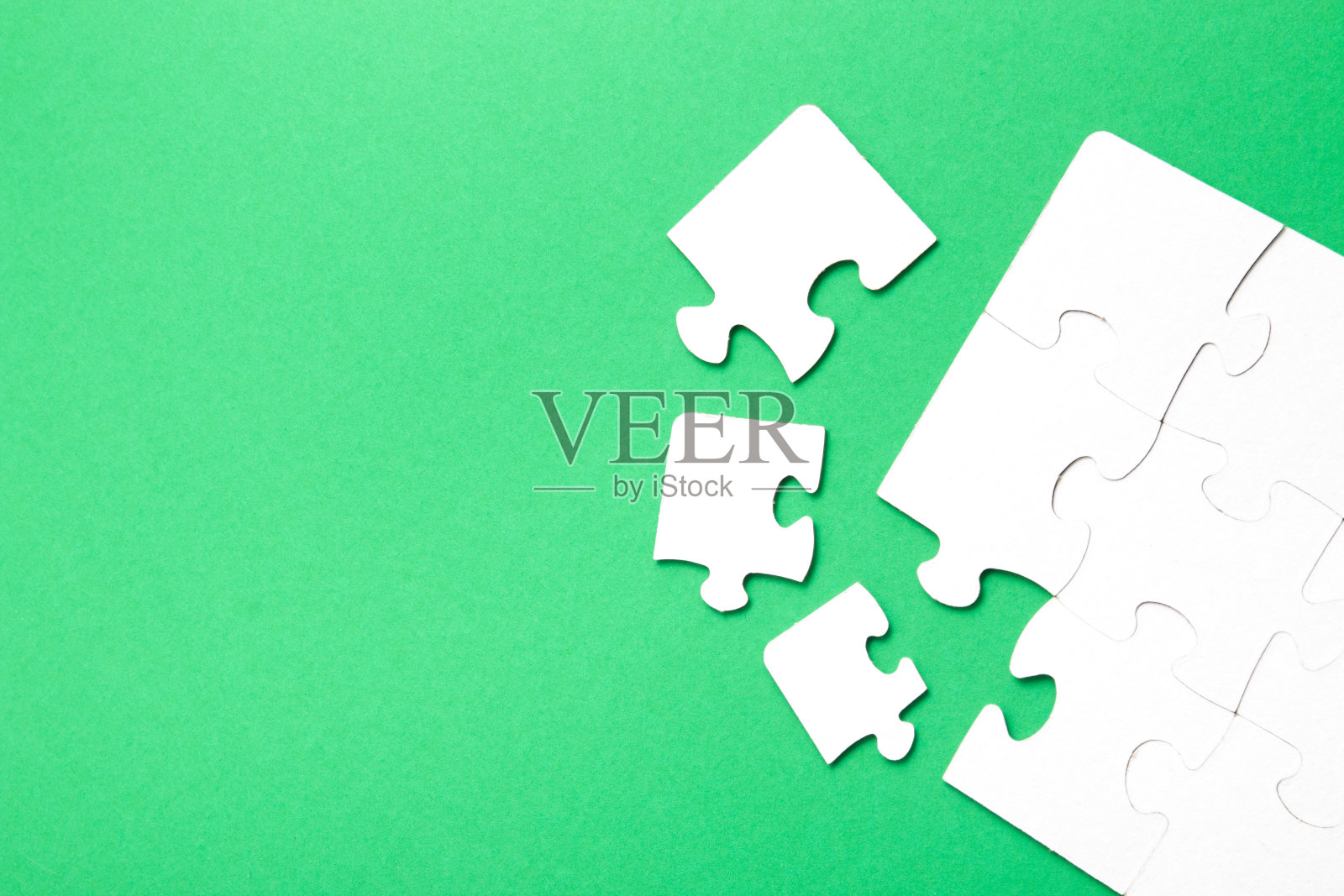 用白色硬纸板在绿色背景上做成的未完成的拼图，几个部分相近，有一块缺失，复制空间，寻找一些合适的部分，团队建设理念照片摄影图片