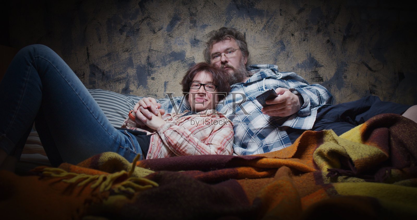 一对成熟的夫妇躺在电视机前看电视照片摄影图片