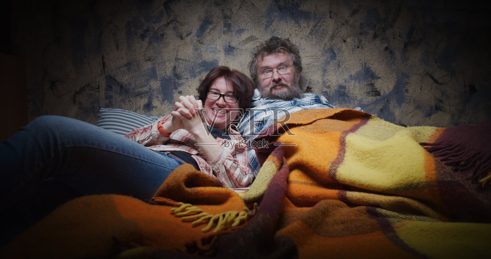 一对成熟的夫妇正斜靠在电视机前看比赛照片摄影图片