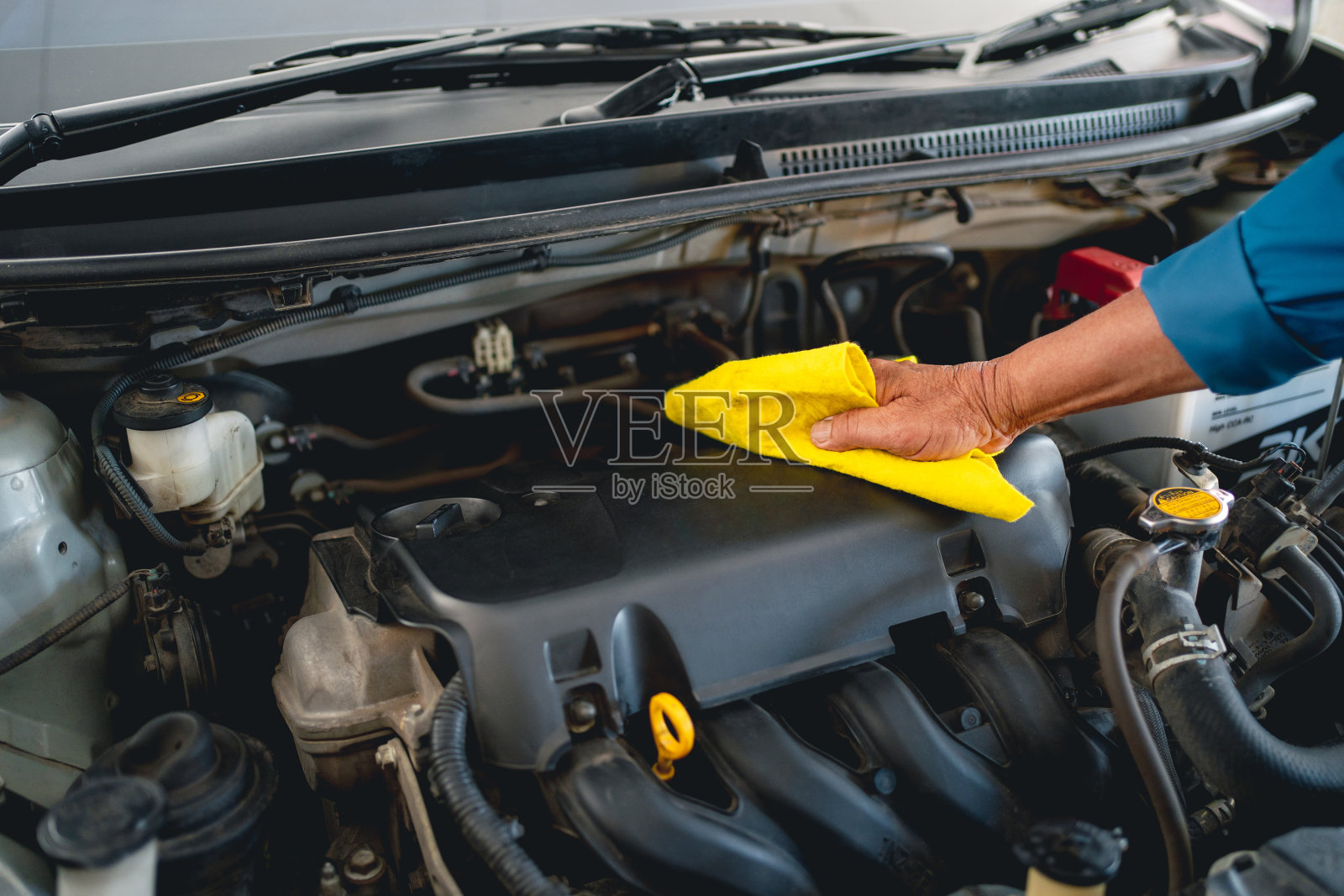 年轻的汽车机修工正在清洗发动机。照片摄影图片