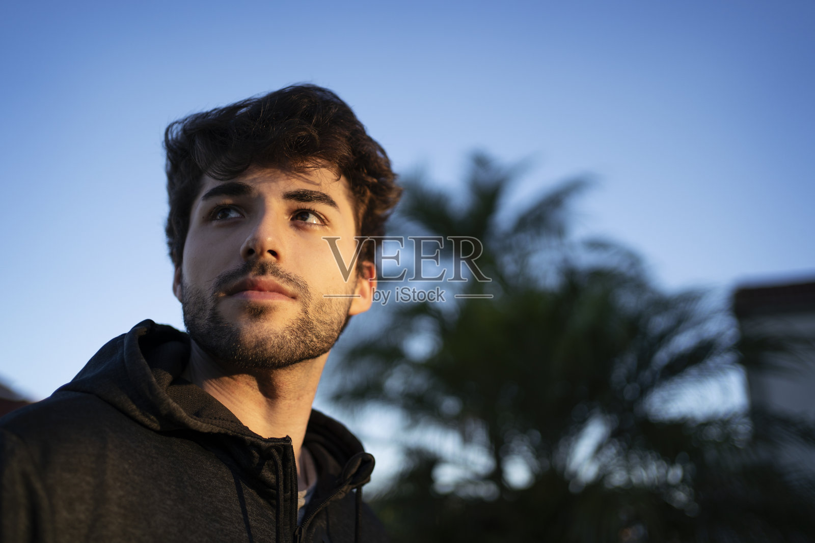 夕阳西下时，一个年轻人站在山顶眺望地平线。想象未来。照片摄影图片