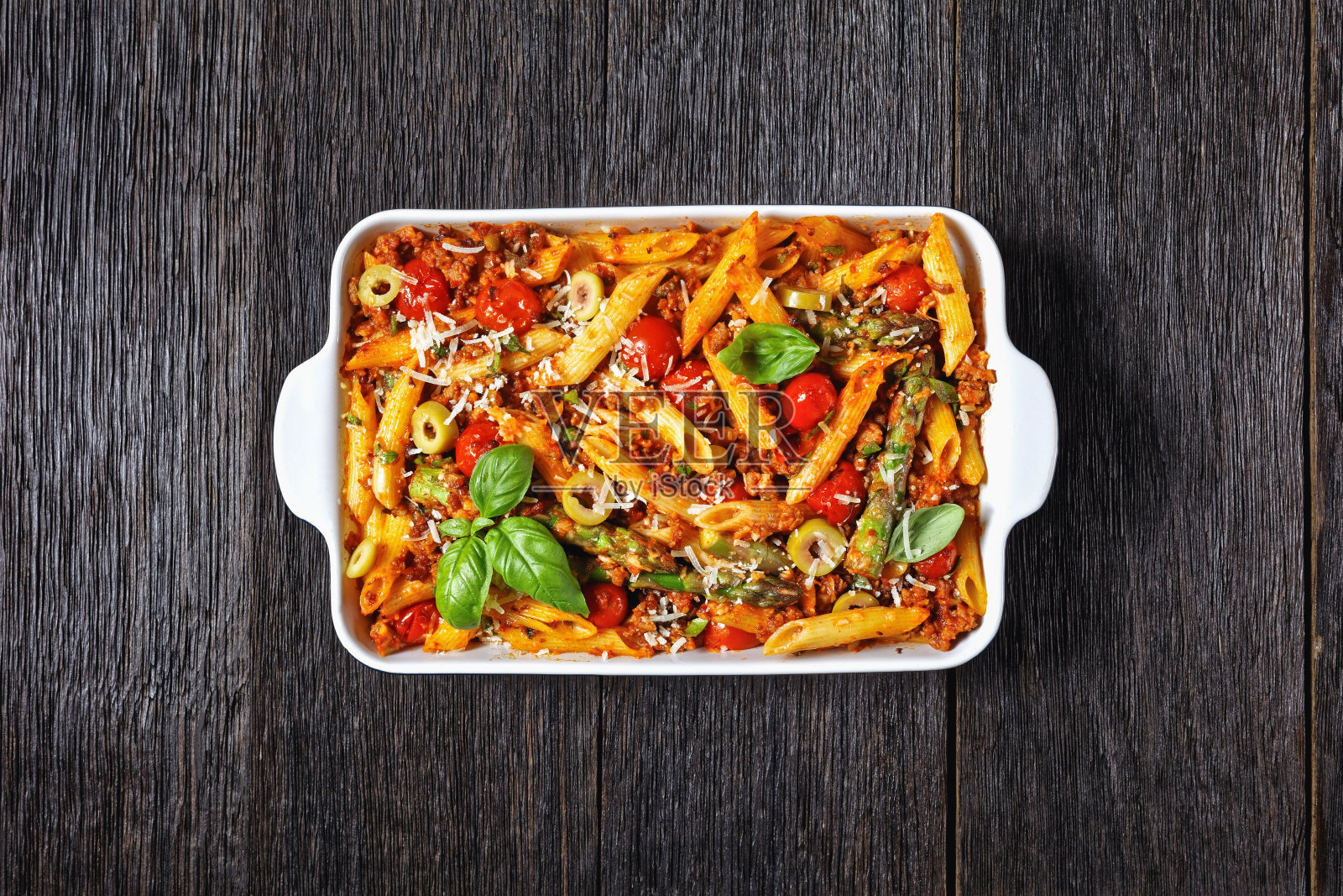 土耳其通心粉和芦笋，西红柿和橄榄一起放在烤盘里，放在深色的木桌上，意大利菜，平铺，空间自由照片摄影图片