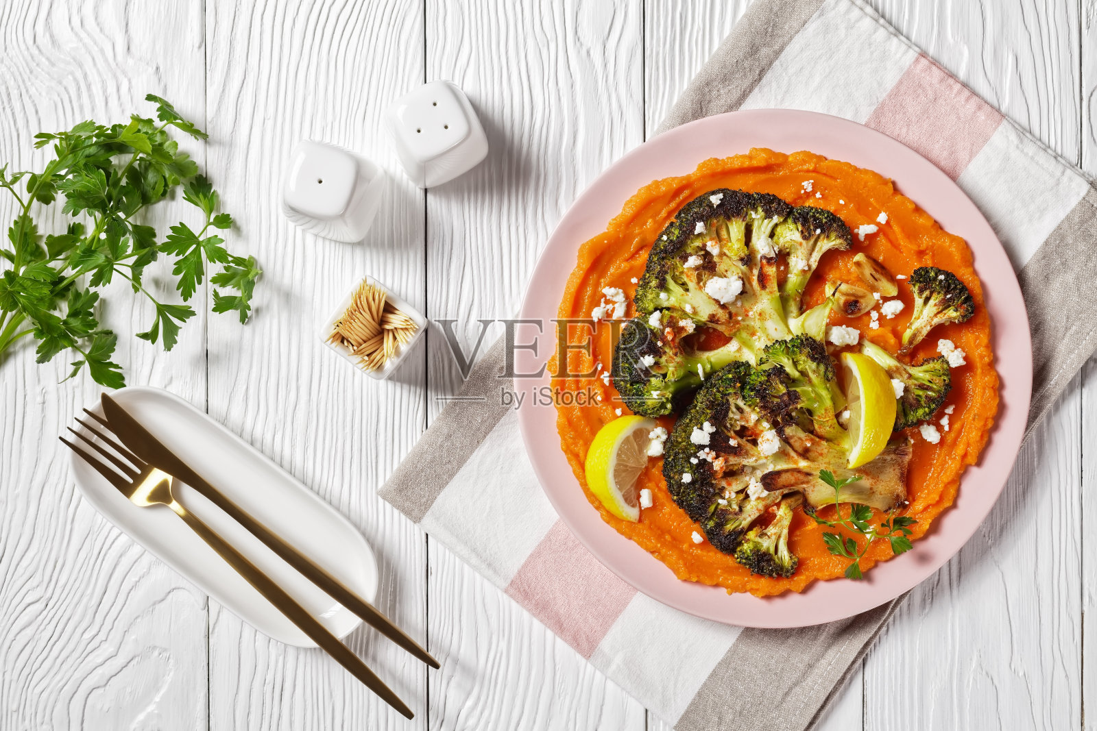 烤花椰菜牛排，南瓜泥，撒上羊乳酪碎，放在白色盘子上，素食食谱照片摄影图片