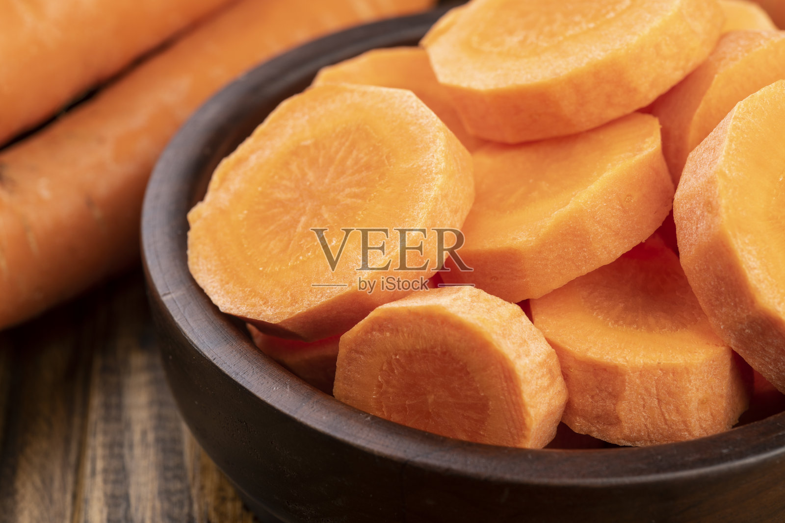 胡萝卜和切片放在木桌上的盘子里照片摄影图片