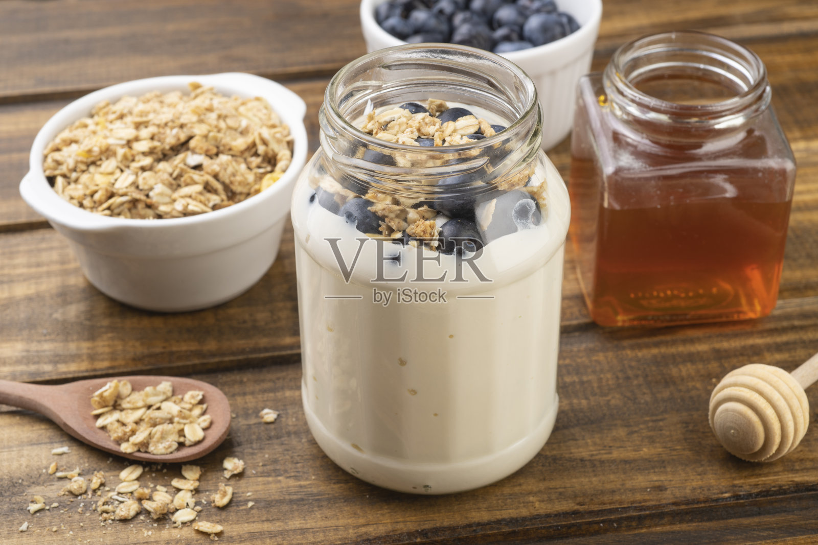 酸奶，格兰诺拉麦片，蓝莓和蜂蜜放在木桌上照片摄影图片